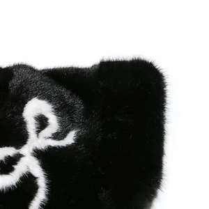 Detailed view of plush black faux fur texture with elegant white bow ribbon accent