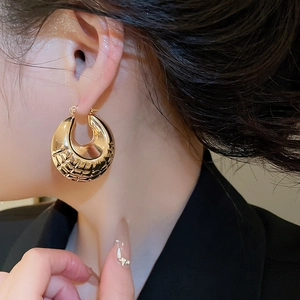 Close-up of a gold geometric textured hoop earring with elegant quilted pattern detailing