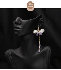Detail of butterfly drop earrings with natural pearls and purple tassels on black model