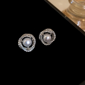 Macro shot of silver pearl earrings with sparkling crystal halo on black velvet