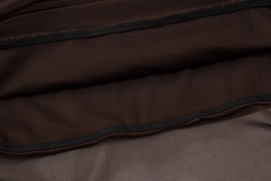 Detail showing dark brown knit fabric spliced with mesh texture and fine stitching