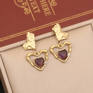 Boucles d'oreilles cœur dorées avec pierre violette sur un plateau de présentation