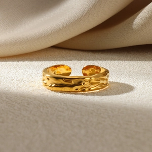 Macro view of adjustable gold open ring featuring irregular lava texture and metallic finish