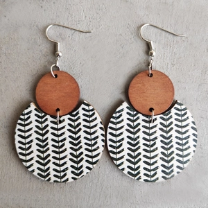 Bohemian wood earrings with black and white arrow patterns on a grey cement background