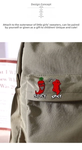 Close-up of funny red chili enamel pins with SPICY text on a green canvas backpack