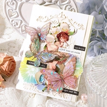 Macro detail of 3D gold-stamped butterfly and fairy stickers for floral scrapbooking