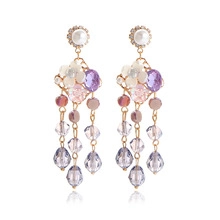 Close-up of golden floral earrings with pearls and colorful crystal beaded tassels