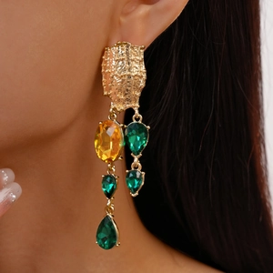 Close-up of vintage geometric gold tassel earrings with green and orange gemstones