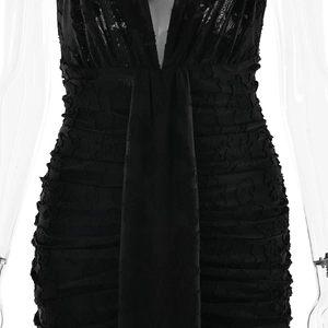 Detailed view of the black bodycon dress featuring deep V-neck and ruched fabric texture