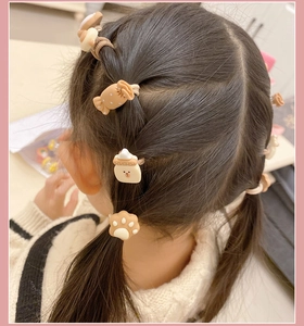 Detailed view of child hair ties with cute cartoon resin charms in warm brown tones