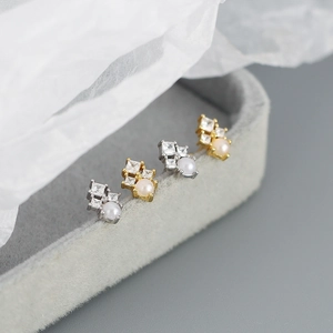 Detail of square zircon studs with imitation pearls in gold and silver finishes