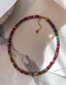 Close-up of 18k gold plated necklace with colorful natural stone beads on marble surface