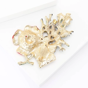 Detailed back view of the golden flower brooch showing the textured metal and pin fastener