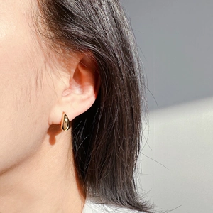 Boucles d'oreilles créoles dorées en forme de goutte portées par un mannequin chic