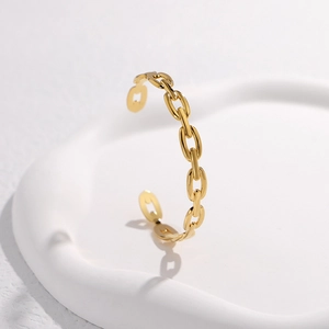 Detail shot of a minimalist gold chain link bangle on a white decorative tray
