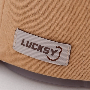 Close-up of khaki cotton twill fabric with embroidered LUCKSY label and smiley face detail