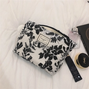 Detail of floral seersucker cosmetic bag with black leaf prints and zipper closure