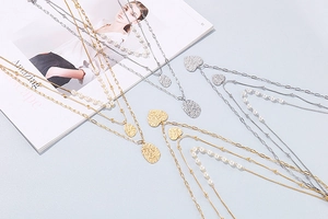 Flat lay of layered gold and silver necklaces with pearls and heart pendants on magazine
