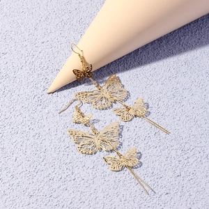 Close-up of gold hollow butterfly tassel earrings with triple layered wings on props
