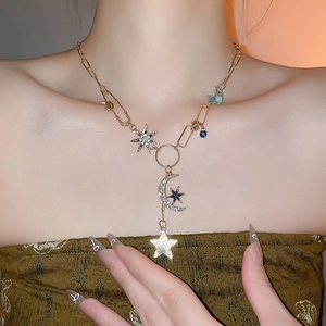 Détail du collier doré avec pendentifs lune et étoile sertis de zircons porté par un mannequin