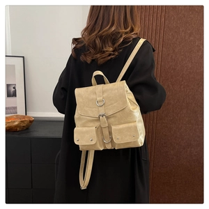 Vue détaillée d'un sac à dos rétro en similicuir crème porté sur un manteau noir