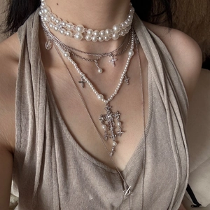 Close-up of layered baroque pearl necklace with silver cross pendants on a female model