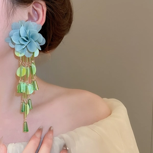 Detail of blue chiffon flower earrings with long sequin tassels on a person