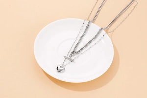 Close-up of double-layered silver steel necklace with chunky chain and heart pendant