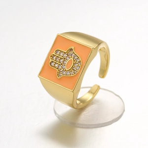 Detail of gold-plated Hamsa ring with orange enamel rectangle and sparkling gemstone inlay