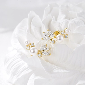 Macro detail of gold floral pearl earrings with marquise zircon on white flower