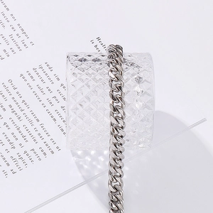 Polished silver Cuban link chain draped on textured glass over vintage book pages