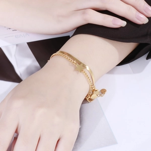 Detail of gold double-layered bracelet with butterfly and star charms on wrist