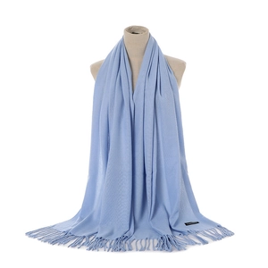 Close-up of light blue cashmere scarf tassels and black material label on soft fabric