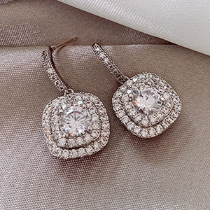 Elegant silver halo drop earrings with sparkling cubic zirconia on champagne silk backdrop