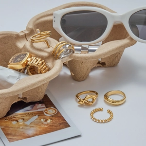 Flache Ansicht von goldenen Schlangenringen und einer Uhr auf einem kreativen Eierkarton