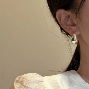 Polished S925 sterling silver hollow teardrop earrings worn by model in side profile view