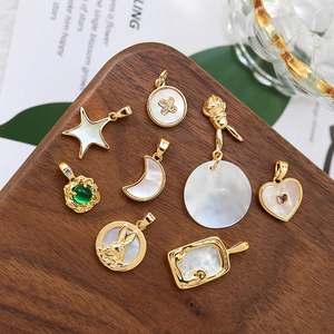 Gold plated shell charms in star and moon shapes on a wooden tray for jewelry making