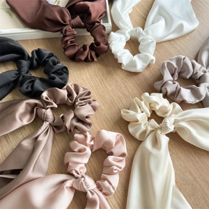 Elegant satin ribbon scrunchies set in various colors on a wooden surface