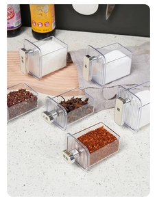 Detail of transparent spice jars with vertical stripes, gold labels and easy-grip handles