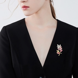 Elegant gold leaf branch brooch with pink gemstones pinned on a black suit lapel