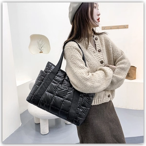 Model wearing a black quilted puffer tote bag with large square stitching detail