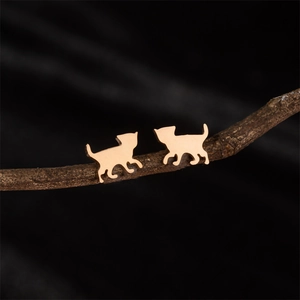 Macro detail of rose gold cat shaped earrings displayed on a rustic wooden branch