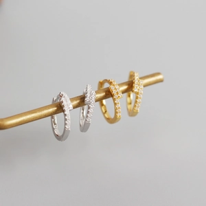 Macro shot of silver and gold geometric hoop earrings with shimmering pavé zircon stones