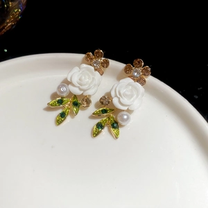 Detailed close-up of white rose earring with green leaf, pearl, and crystal inlay