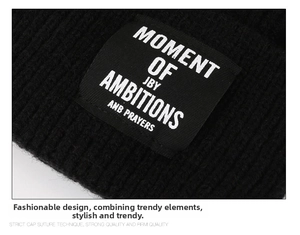 Detail of the black beanie featuring a woven label with white text and knit texture