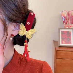 Detail of red velvet butterfly hair clip with golden tassels and heart pearl earrings