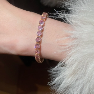 Close-up of pink cubic zirconia tennis bracelet in gold plating on female wrist