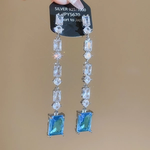 Detail of 925 silver earrings with sparkling white zircons and a blue rectangular gemstone