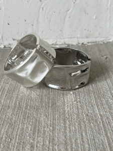 Detail of wide metal bangles showing matte satin and high-gloss polished hammered textures