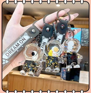 Detail of hand holding creative astronaut liquid keychain with black Dream On silicone strap
